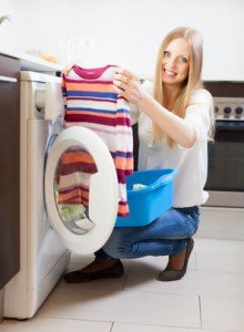 Frau mit Wäsche vor Waschmaschine